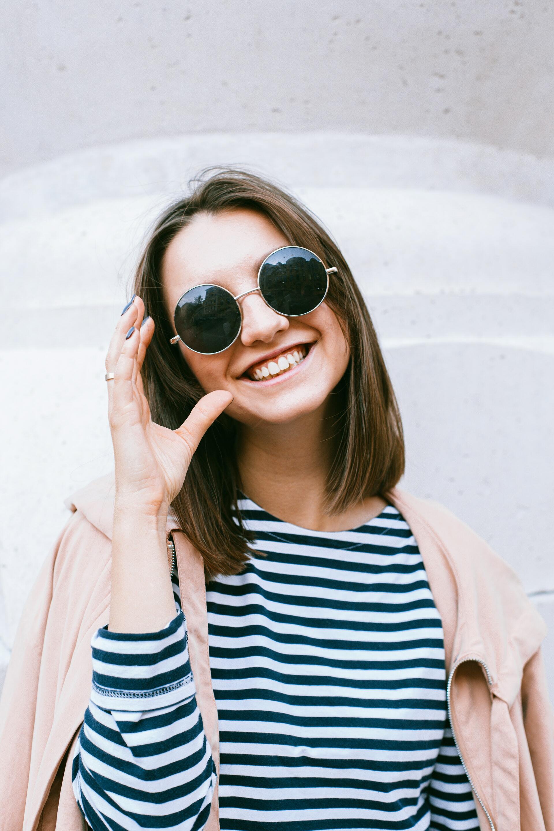Woman in white and black striped shirt wearingg black sunglasses